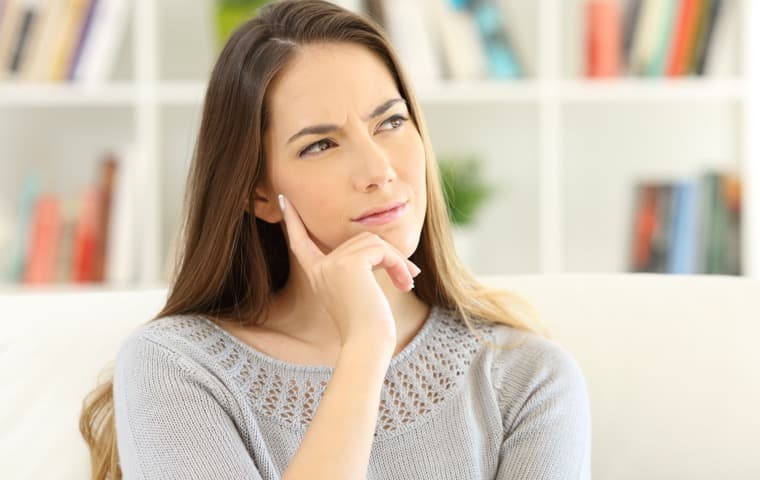 Frau, die den Zeigefinger an die Wange legt. Sie denkt nach