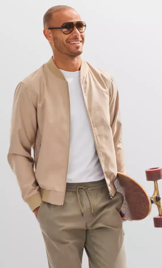 Mann trägt eine beigen Blouson und beige Hose.