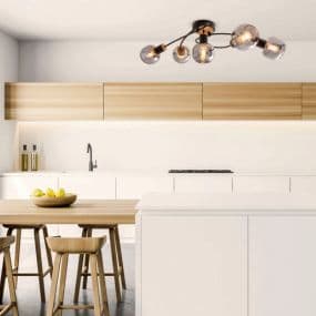 Moderne Küche mit Holzschränken, Insel und Hockern, auffällige Deckenlampe mit mehreren Glühbirnen.