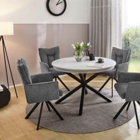 Runder Tisch mit vier grauen Stühlen, Vase mit Blumen darauf, moderne Lampe und Wanduhr im Hintergrund.