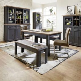 Esszimmer mit Holztisch, Bank, Stuhl und schwarzen Schränken, dekoriert mit Vasen und Geschirr auf hellem Teppich
