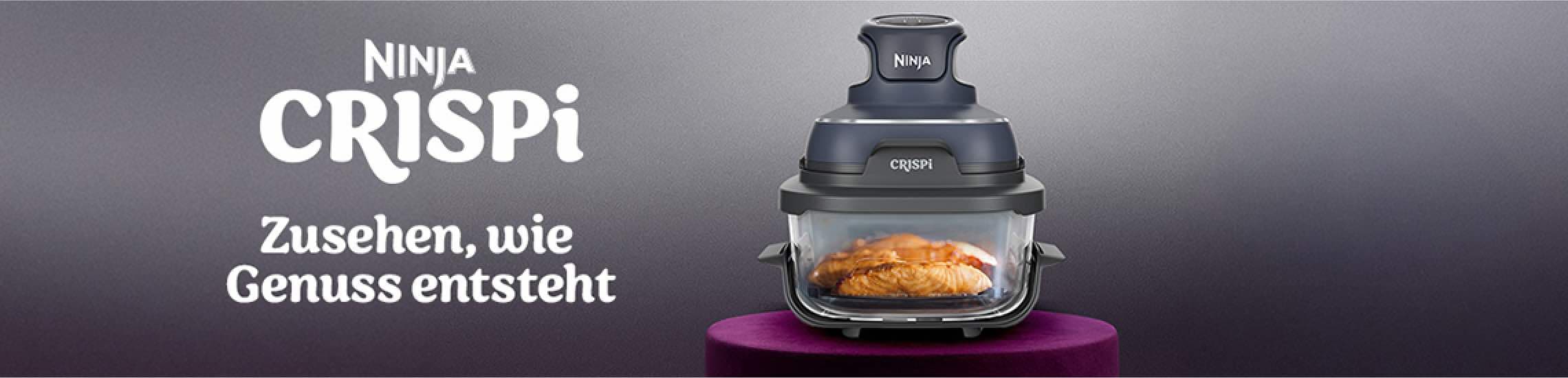 Ninja Crispi – Zusehen, wie Genuss entsteht. AirFryer mit gebratenem Hähnchen im Glaskasten auf einem lila Podest.