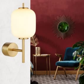 Goldene Wandleuchte vor roter Wand, daneben blauer Sessel und goldener Beistelltisch mit Dekoration.