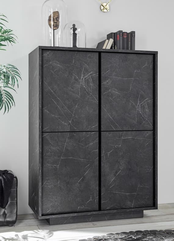Hoher, dunkler Schrank mit vier Türen in Steinoptik, darauf Glasglocken mit Dekofiguren und Bücher im modernen Wohnzimmer