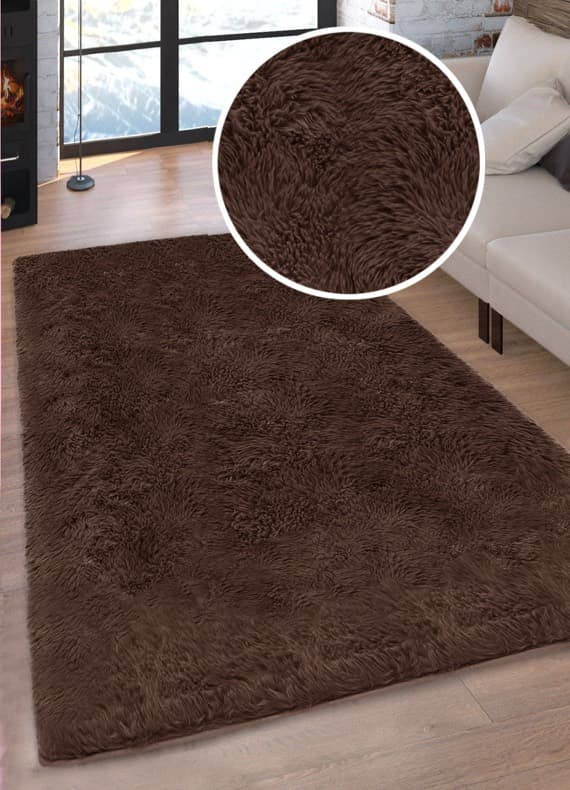 Großer brauner Hochflorteppich im Wohnzimmer neben hellem Sofa, Detailausschnitt zeigt dichten Flor