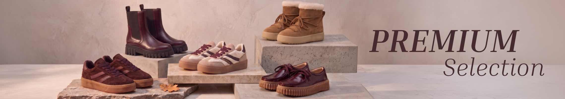 Premium Selection – mehrere Paar herbstliche Schuhe auf Podesten in warmen Brauntönen arrangiert