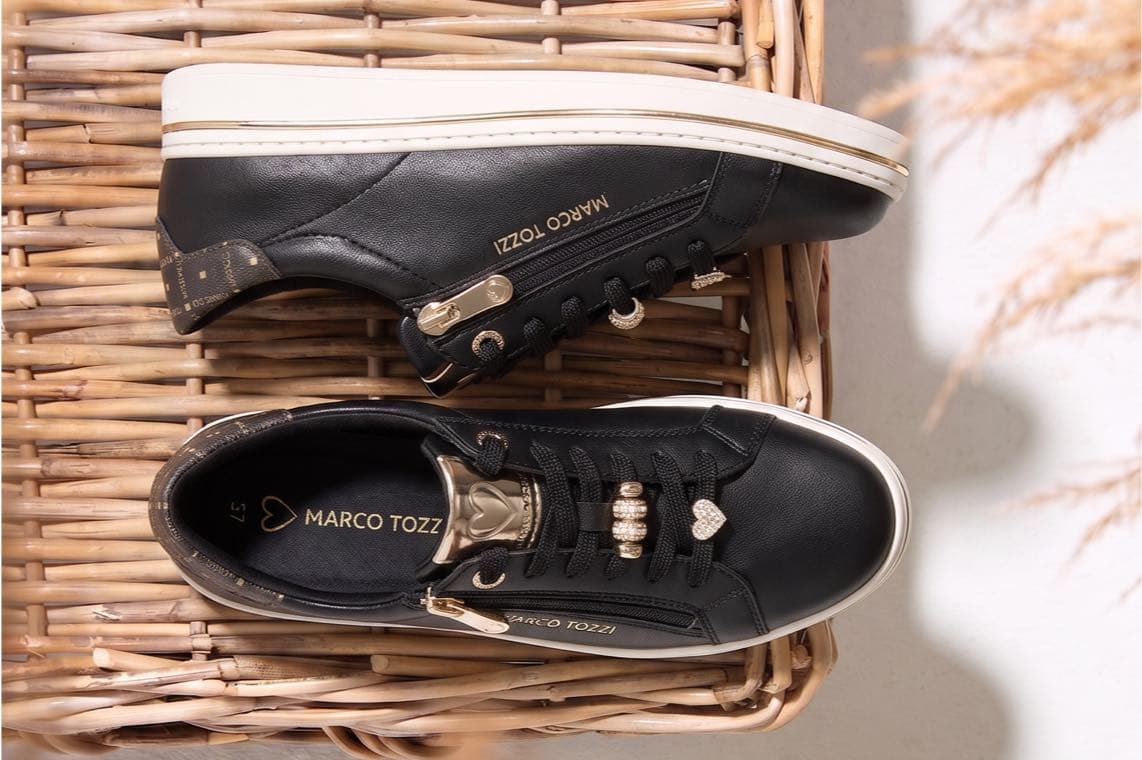 Marco Tozzi Sneaker in Schwarz mit weißer Sohle und goldenen Details, von oben auf geflochtenem Untergrund gesehen