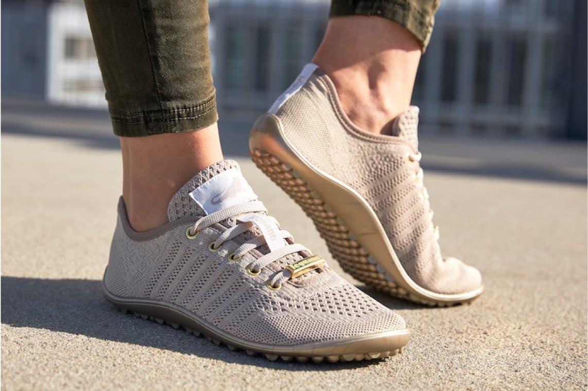 Person trägt beigefarbene Schnürschuhe mit feiner Lochstruktur, ein Fuß steht flach, der andere ist leicht angehoben
