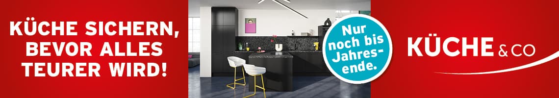 Küche sichern, bevor alles teurer wird – moderne schwarze Einbauküche mit Kochinsel und zwei weißen Barhockern
