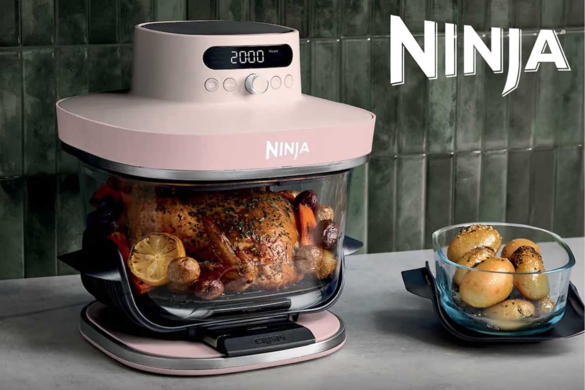 Ninja Heißluftfritteuse mit digitaler Anzeige gart ein ganzes Hähnchen mit Gemüse, daneben Schale mit Kartoffeln