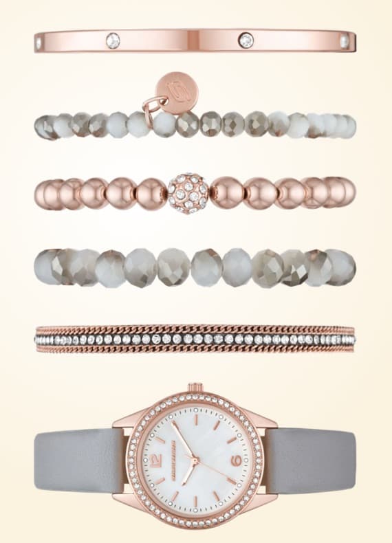 Uhr mit grauem Armband und mehrere passende Armbänder in Rosétönen in einer Reihe angeordnet