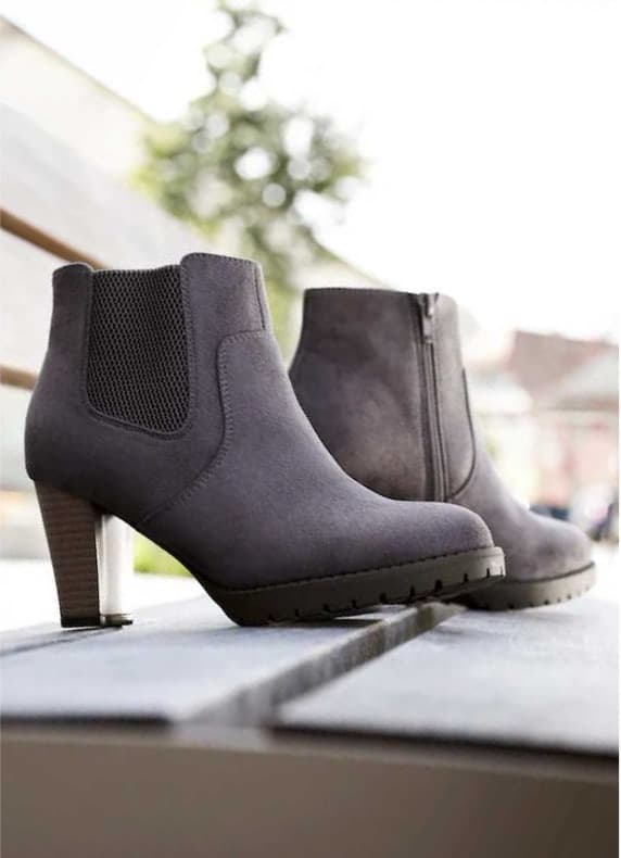 Grau melierte Damen-Stiefeletten mit Blockabsatz stehen auf einer Bank im Freien