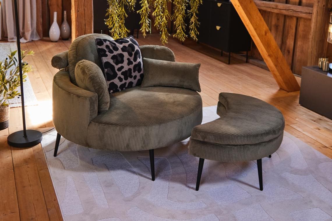 Rundes Sofa mit halbmondförmigem Hocker und Leopardenkissen in hellem Dachwohnzimmer auf großem Teppich