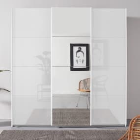 Ein moderner weißer Kleiderschrank mit Schiebetüren und Spiegel. Der Boden ist mit einem Teppich bedeckt.