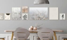 Ein eleganter Essbereich mit einem langen Tisch und zwei modernen Stühlen. An der Wand hängen mehrere Bilder in sanften Farben, die eine harmonische und künstlerische Atmosphäre schaffen.