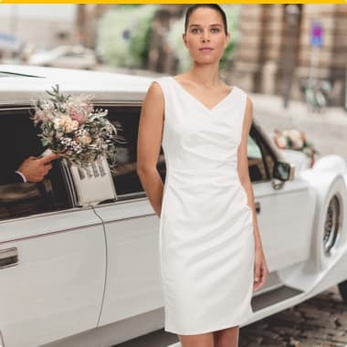 Frau in weißem Kleid steht vor weißer Limousine, Mann hält Blumenstrauß aus dem Fenster