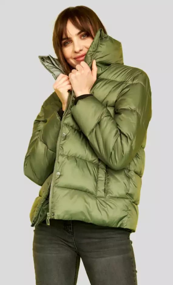 Frau trägt eine olivgrüne Daunenjacke und schwarze Jeans.