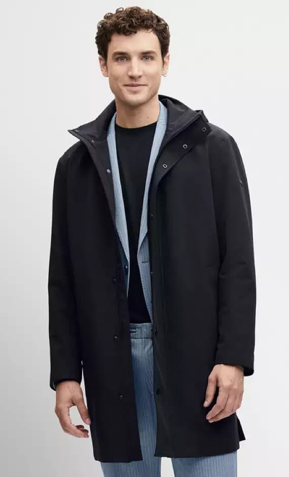 Mann trägt schwarzen halblangen Mantel über blauem Sakko und Jeans.