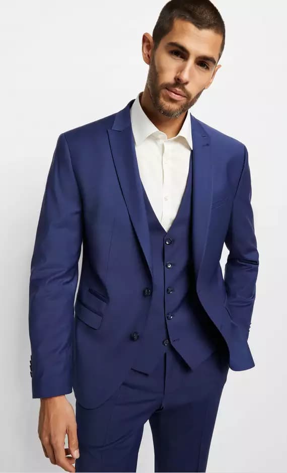 Mann trägt eleganten blauen Anzug mit Weste und weißem Hemd.