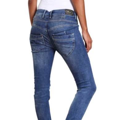 Frau von hinten in blauer Jeans und weißem Oberteil, Hände seitlich am Körper