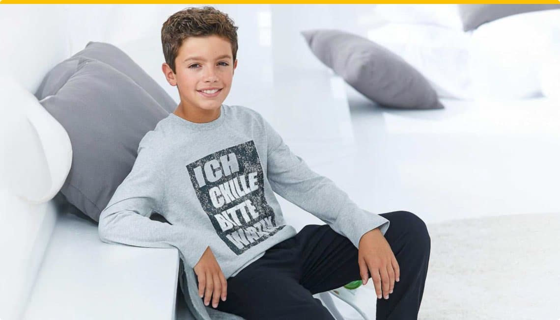 Ich chille, bitte nicht stören – Junge in grauem Langarmshirt sitzt auf Sofa