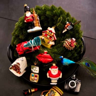 Grüner Weihnachtskranz dekoriert mit bunten Anhängern wie Weihnachtsmann,Lippenstift und Pfauenfeder