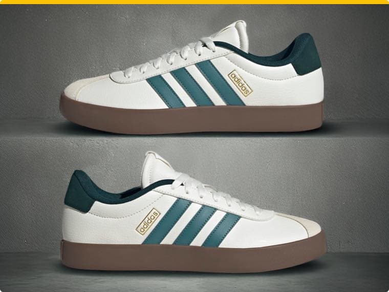 Zwei weiße Adidas Sneaker mit grünen Streifen und brauner Sohle vor grauem Hintergrund