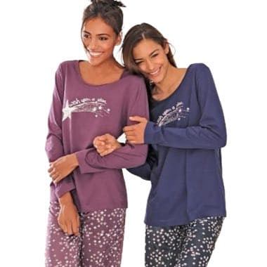 Zwei Personen in lila und blauen Pyjamas mit Sternenmuster halten sich am Arm und stehen nebeneinander.