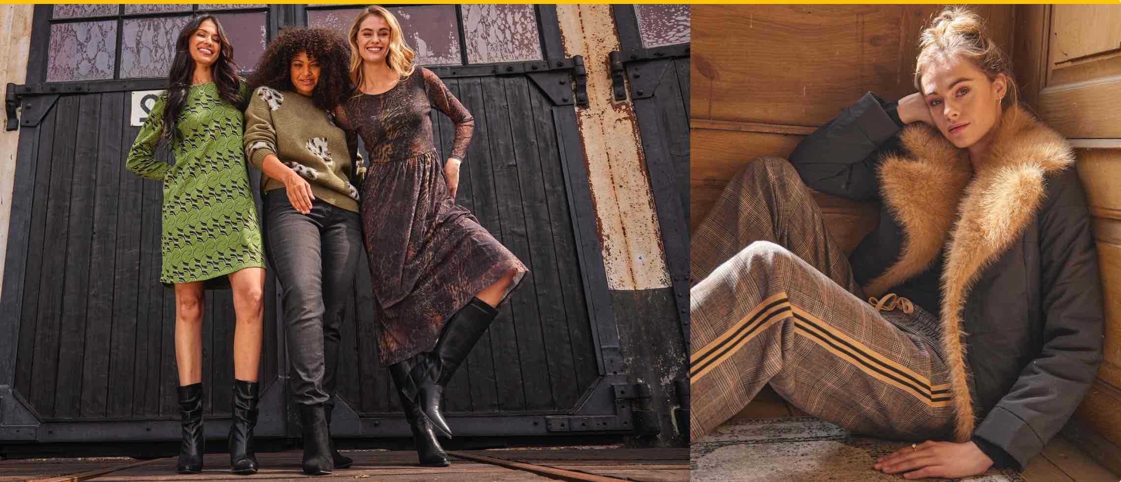 Drei Frauen in Herbstkleidung vor Holztüren. Frau in karierten Hosen und Jacke mit Fellkragen sitzt in Holzkabine.