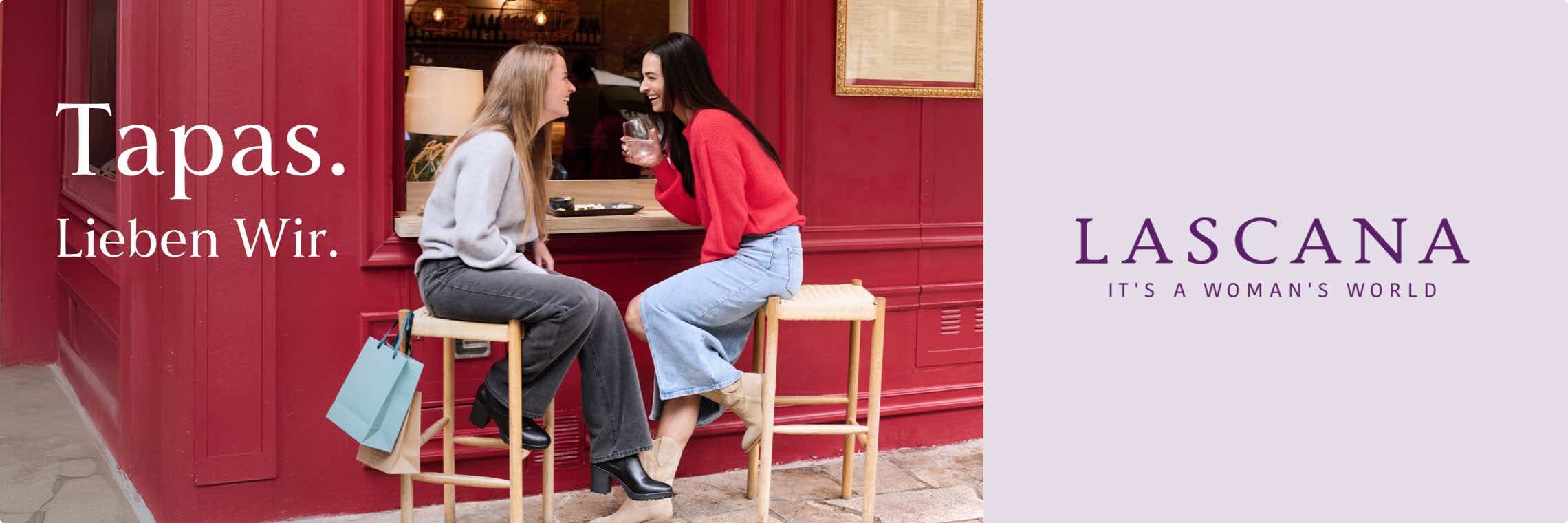 Tapas. Lieben Wir. Zwei Frauen sitzen an einer roten Bar und genießen Tapas, eine trägt Einkaufstüten. LASCANA It's a woman's world.