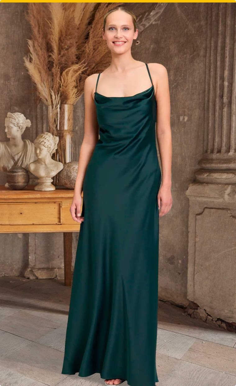 Frau in langem, dunkelgrünem Kleid mit dünnen Trägern steht vor antiken Statuen und Trockenblumen-Dekoration