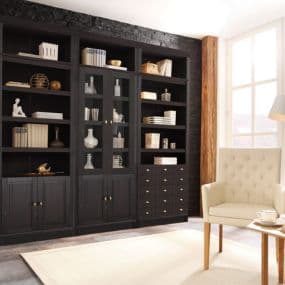 Schwarzes Bücherregal voller Dekorationen neben einem beigen Sessel im hellen Raum