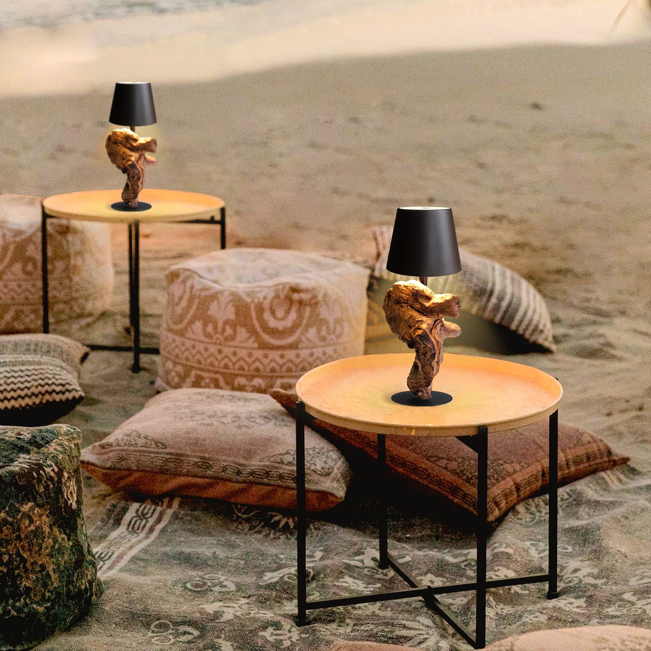Zwei Tische mit Lampen und dekorativen Kissen auf einem Teppich am Strand.