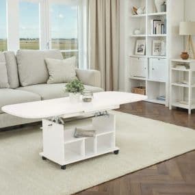 Modernes Wohnzimmer mit weißem Hebetisch, grauem Sofa, weißem Teppich und Regal im Hintergrund.