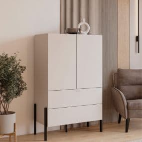 Moderner weißer Schrank mit zwei Türen und zwei Schubladen, daneben ein Sessel und eine Pflanze