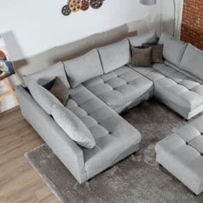 Graues Ecksofa mit braunen Kissen auf Teppich in modernem Wohnzimmer.
