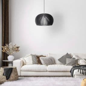 Modernes Wohnzimmer mit weißem Sofa, schwarzen Kissen und hängender Lampe vor weißer Wand.