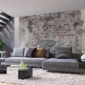 Modernes Wohnzimmer mit grauem Sofa, gemusterten Kissen und rustikalem Wandbild. Beistelltisch und Teppich ergänzen das Design.