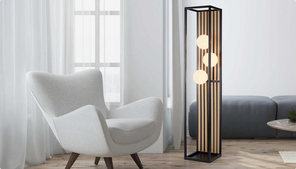 Modernes Wohnzimmer mit weißem Sessel und Stehleuchte mit drei Kugellichtern vor einem Fenster.