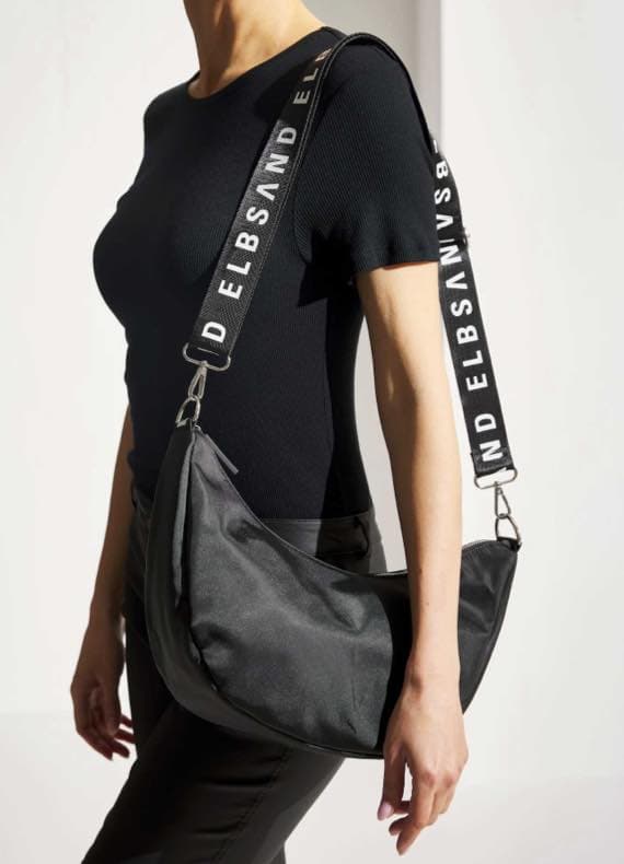 Person mit schwarzer Tasche, breite Träger mit Aufschrift "ELBSAND", trägt schwarzes Shirt.