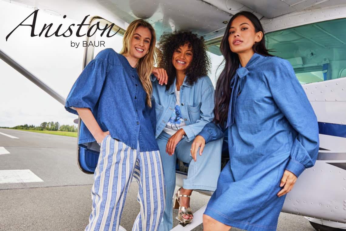 Aniston by BAUR – Drei Frauen in blauer Kleidung posieren vor einem Flugzeug.