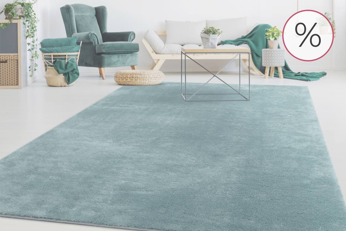 % – Wohnzimmer mit grünem Sessel, Korb und blauem Teppich