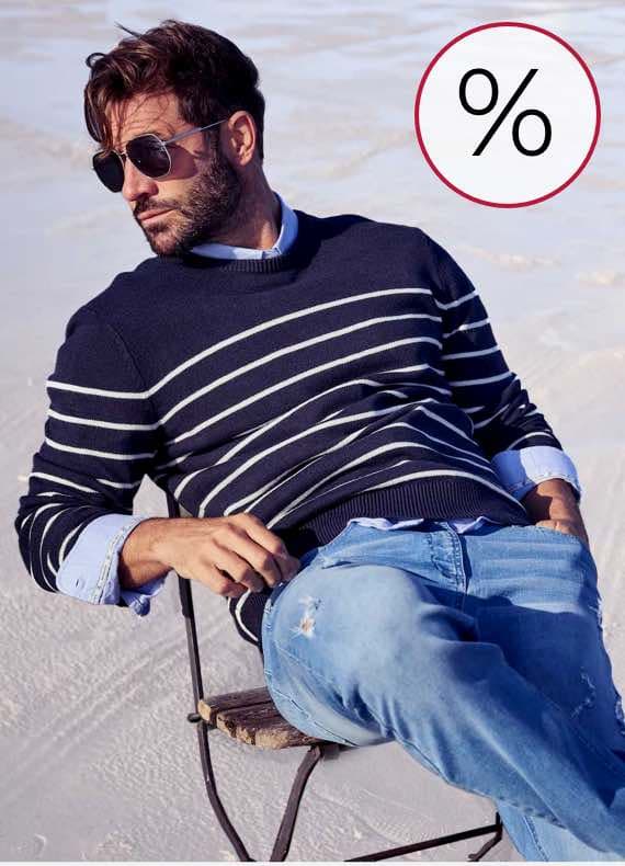 Prozentzeichen – Mann in gestreiftem Pullover und Jeans sitzt entspannt auf einem Stuhl im Freien