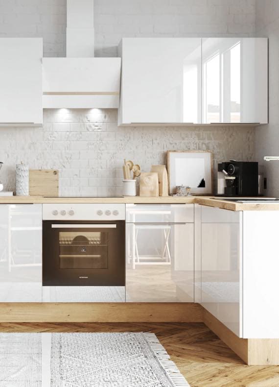 Moderne Küche mit weißen Hochglanz-Schränken, Holzarbeitsplatte und eingebautem Ofen. Kaffeemaschine und Küchenutensilien auf der Arbeitsfläche.