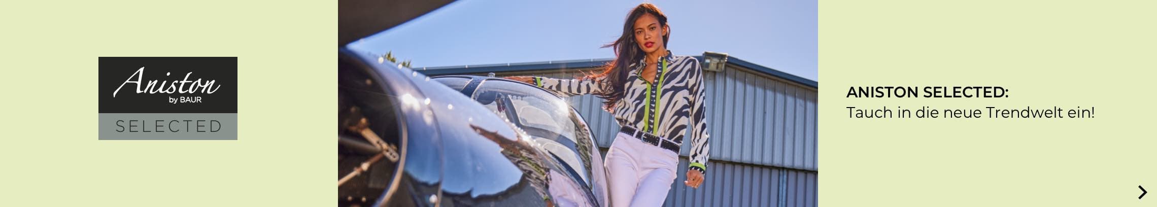 ANISTON SELECTED: Tauch in die neue Trendwelt ein! Frau in gemustertem Oberteil und weißer Hose lehnt an einem Auto.