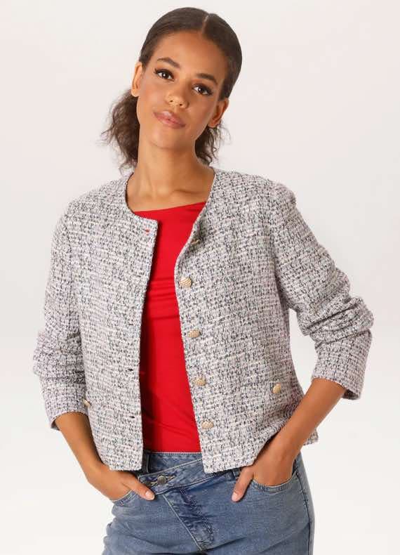 Frau trägt grauen Blazer über rotem Shirt und blaue Jeans.