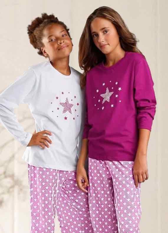 Zwei Kinder tragen passende Pyjamas mit Sternenmotiven, eines in Weiß, das andere in Pink.