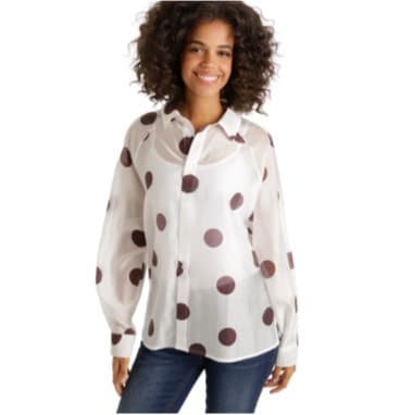 Frau trägt weiße Bluse mit großen braunen Punkten und blaue Jeans.