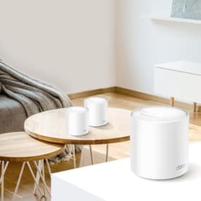Modern Wohnzimmer mit drei weißen WLAN-Routern auf einem Holztisch. Im Hintergrund Sofa und Sideboard.