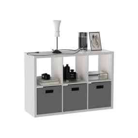 Weißes Regal mit drei grauen Körben, dekoriert mit Lampe, Buch und Bilderrahmen oben.